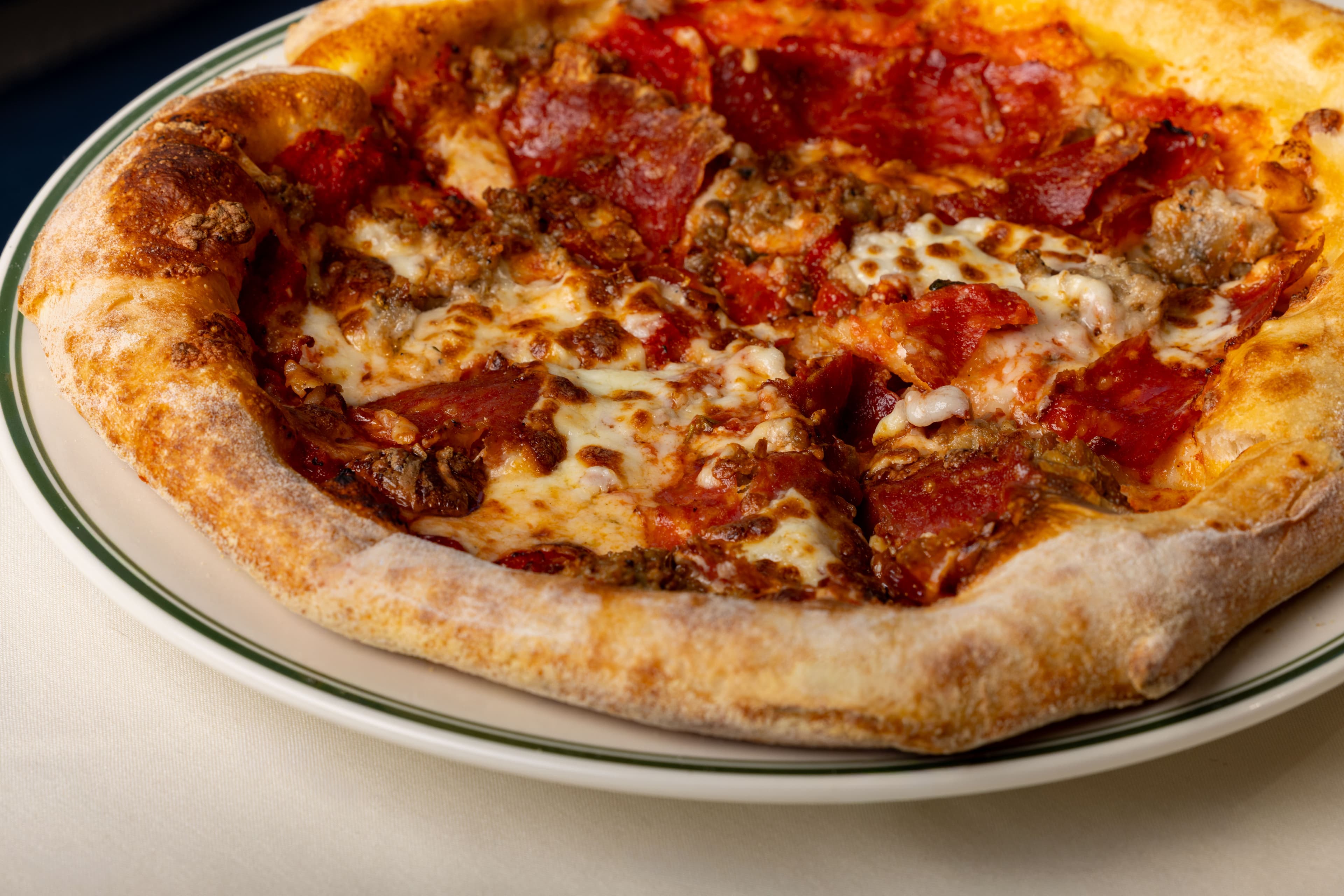 Wood-fired pizza with pepperoni, sausage and bubbling mozzarella