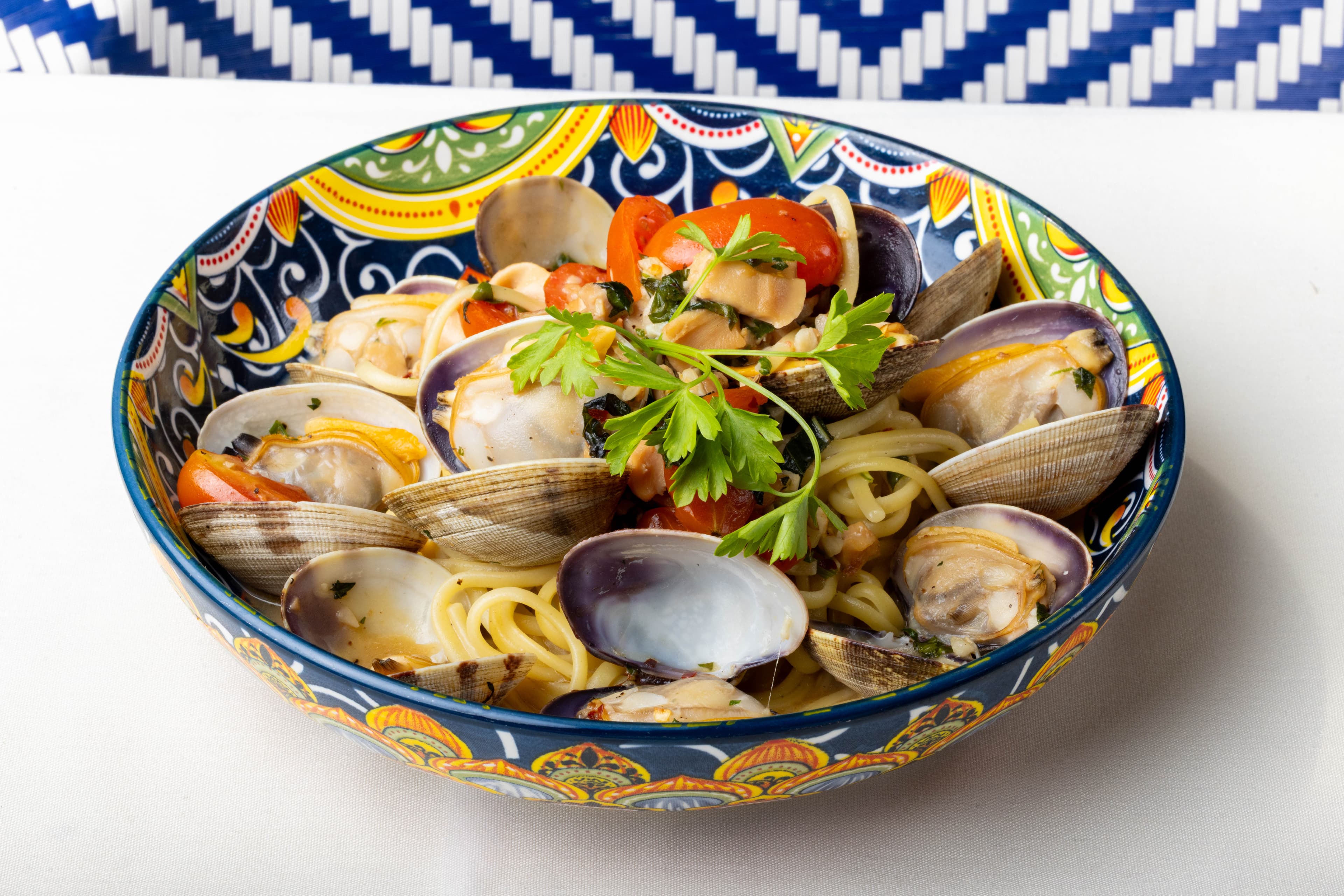 Spaghetti with fresh clams and cherry tomatoes in a hand-painted Sicilian bowl